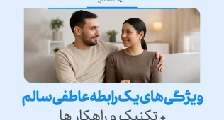 زوجی نشسته روی مبل با لبخند و نگاه صمیمی؛ نمادی از محبت و اعتماد در یک رابطه سالم عاطفی